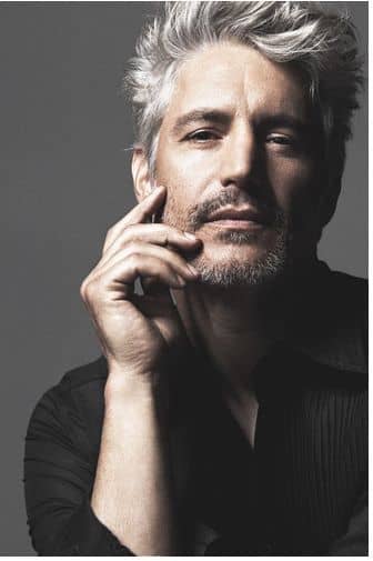 head shot grey color hair man with with his hand on his face